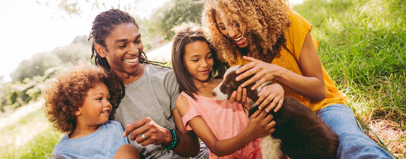 A happy young family as they gather around a puppy.