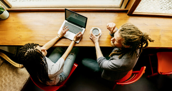 Woman and man sitting at a table in front of a laptop