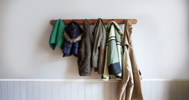 multi-sized child and adult coats hang on a coat rack