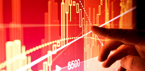 Finger pointing at market data on a large display screen