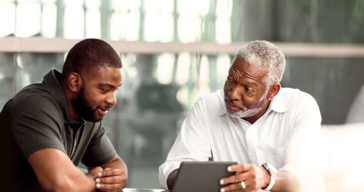 two men, father and son, discuss something they are viewing online