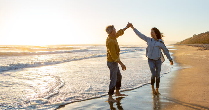 a couple walks on the beach holding hands