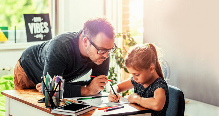 A dad and his young daughter writing in a notebook.