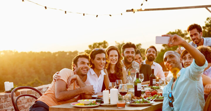 Friends take a selfie while having dinner outdoors