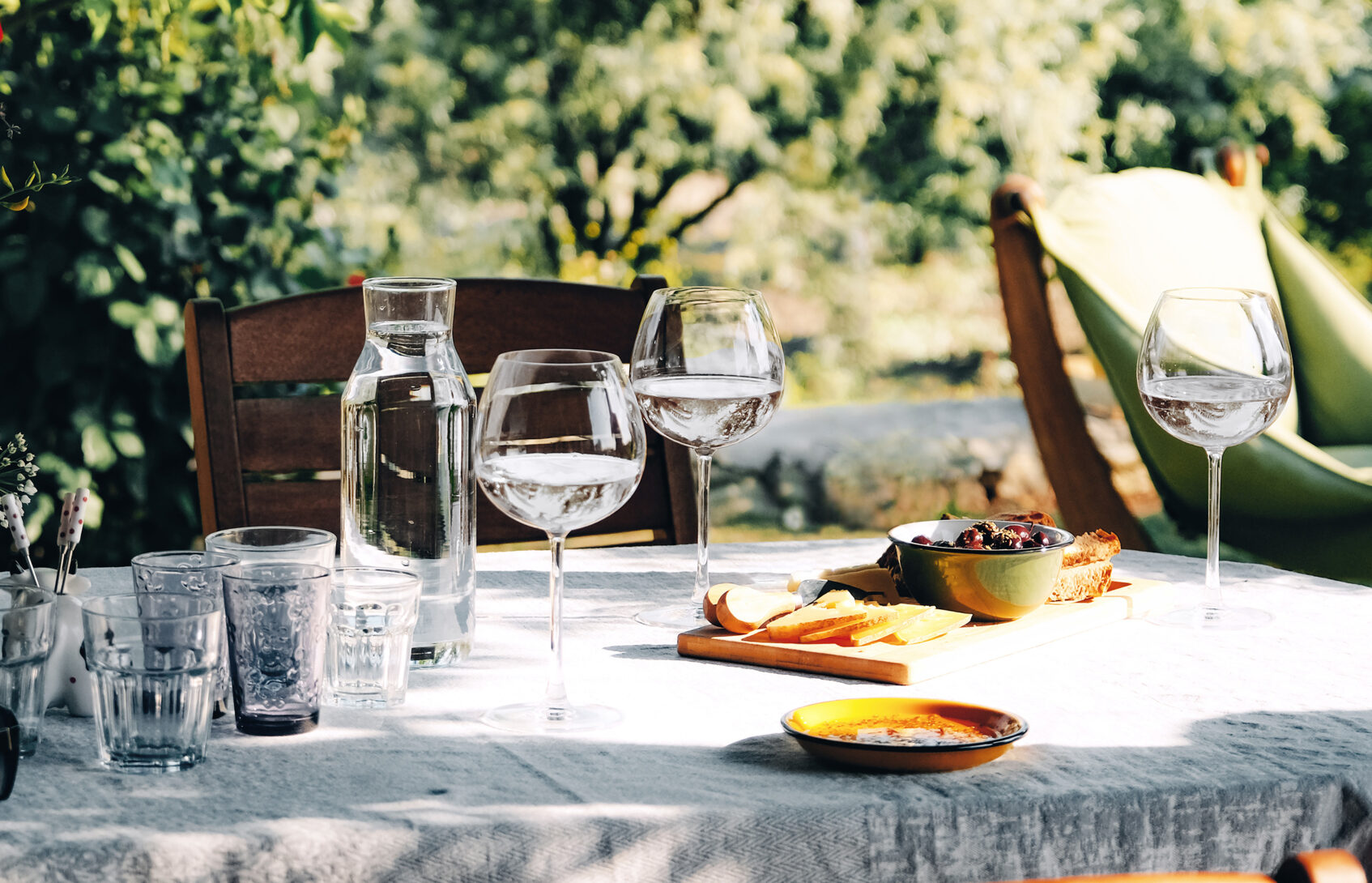 A sunlit oval table is set with snacks, glasses, and small plates to welcome family