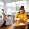 A teenage girl scans her paycheck with her cell phone.