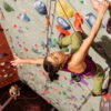 A woman climbing a colorful indoor rock wall
