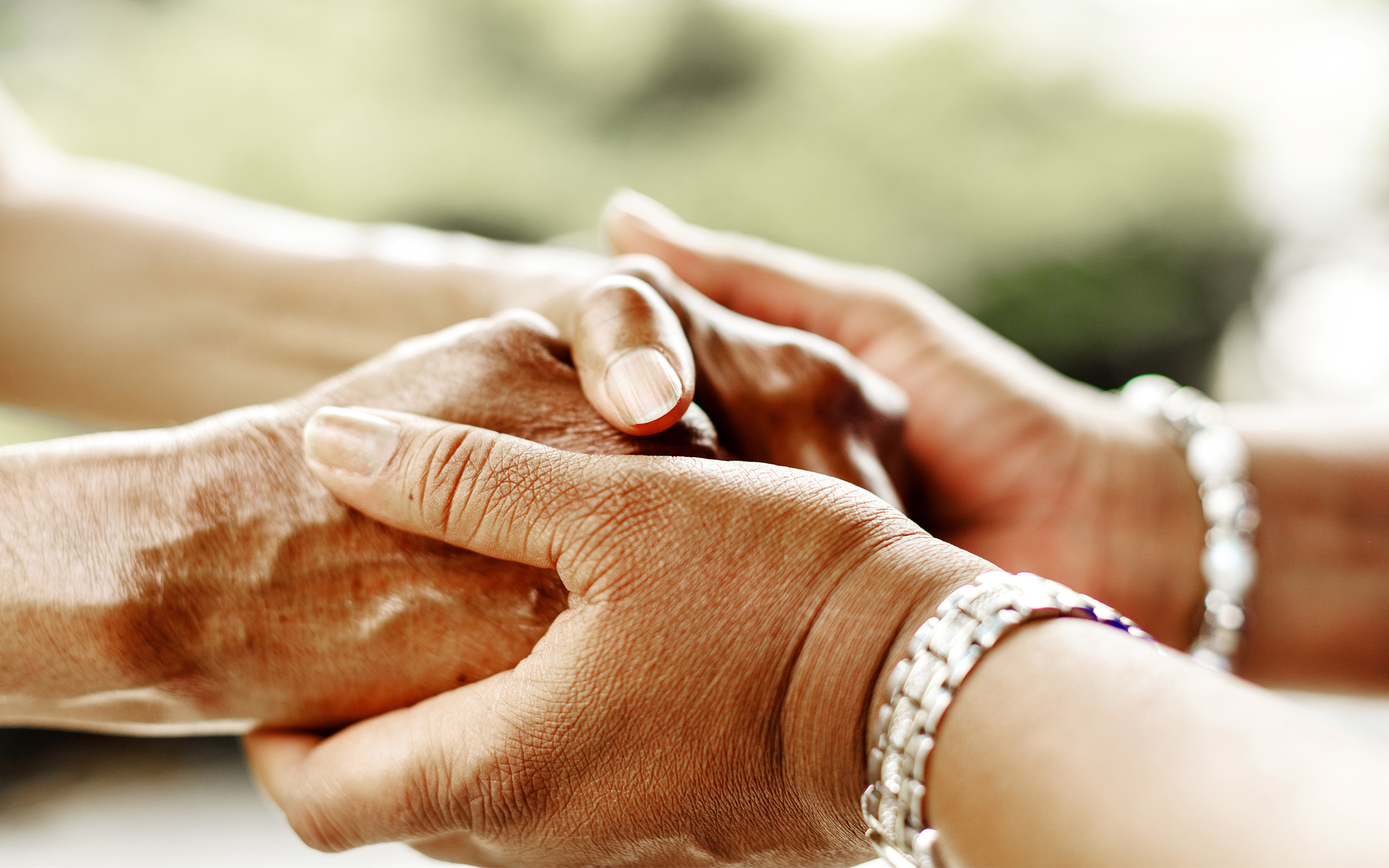 One person’s hands holding another person’s hands