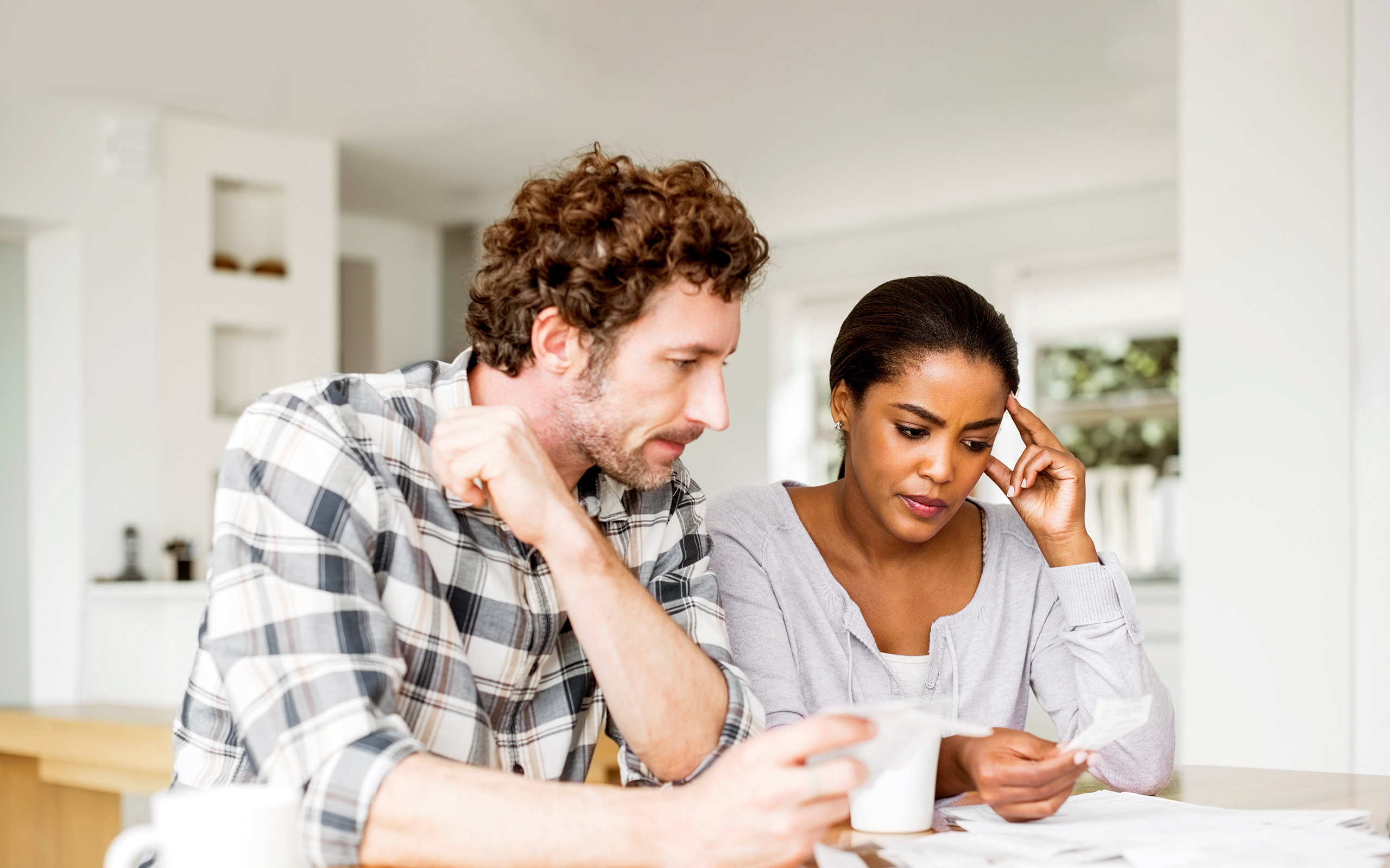 A couple sitting at the kitchen table looking at a receipt