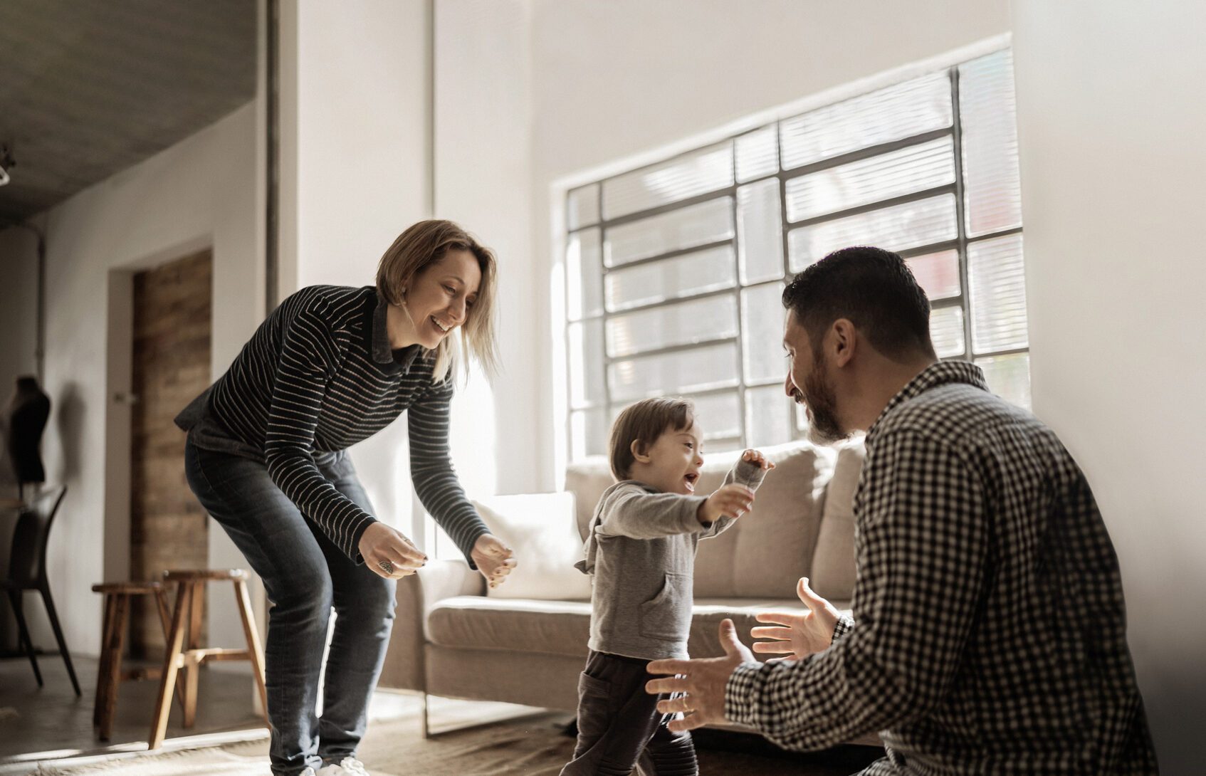 A young boy with a disability walking toward his father in the living room