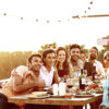 Smiling man taking group selfie on mobile phone at dinner party