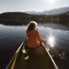 Woman paddling a canoe on a lake. Read about Solo aging and independent living: What to know and how to help prepare