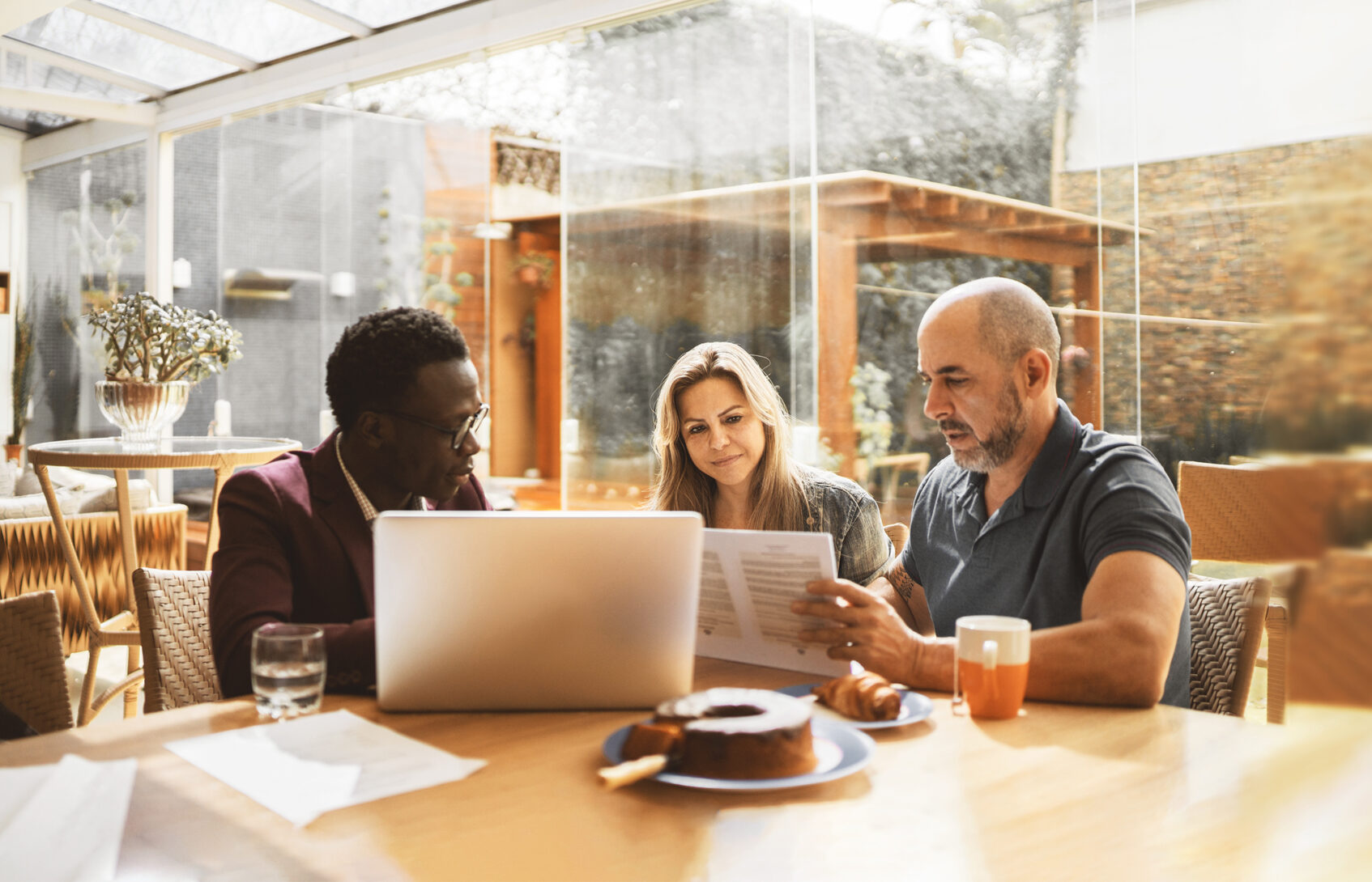 A couple sitting at a table with a financial advisor reviewing documents.