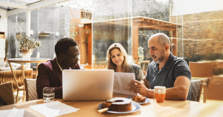 A couple sitting at a table with a financial advisor reviewing documents.