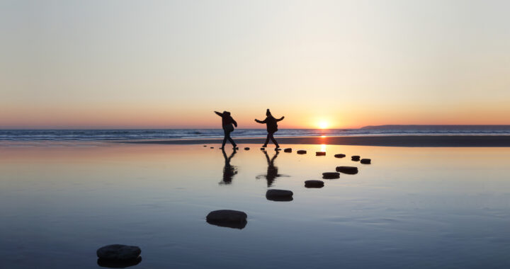 People walking on rocks on lake.