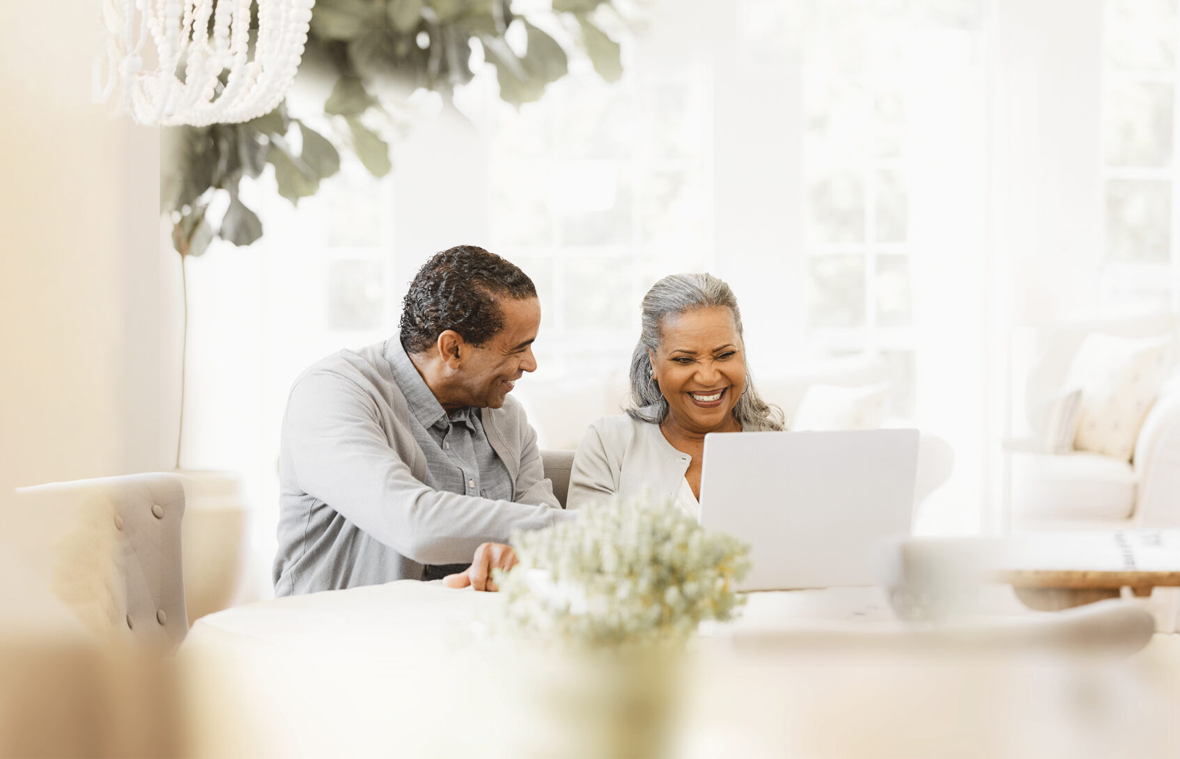 A husband and wife looking at a computer screen and smiling.