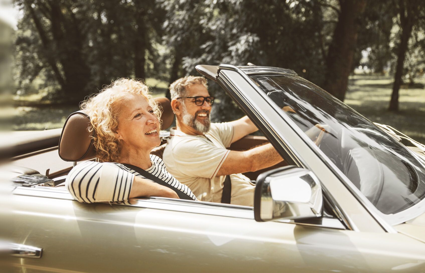 Smiling couple driving in a convertible.