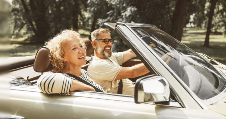 Smiling couple driving in a convertible.