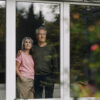 Senior couple behind windowpane of their home