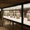 A woman views a series of floral urns at a museum exhibition Read about Noteworthy art museum exhibitions to visit this season