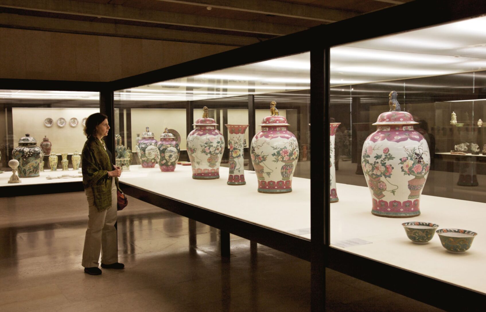 A woman views a series of floral urns at a museum exhibition