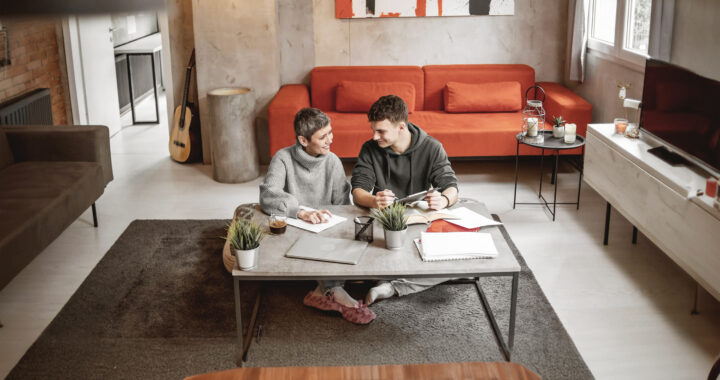 A mother and son review finances while sitting on the floor of their living room