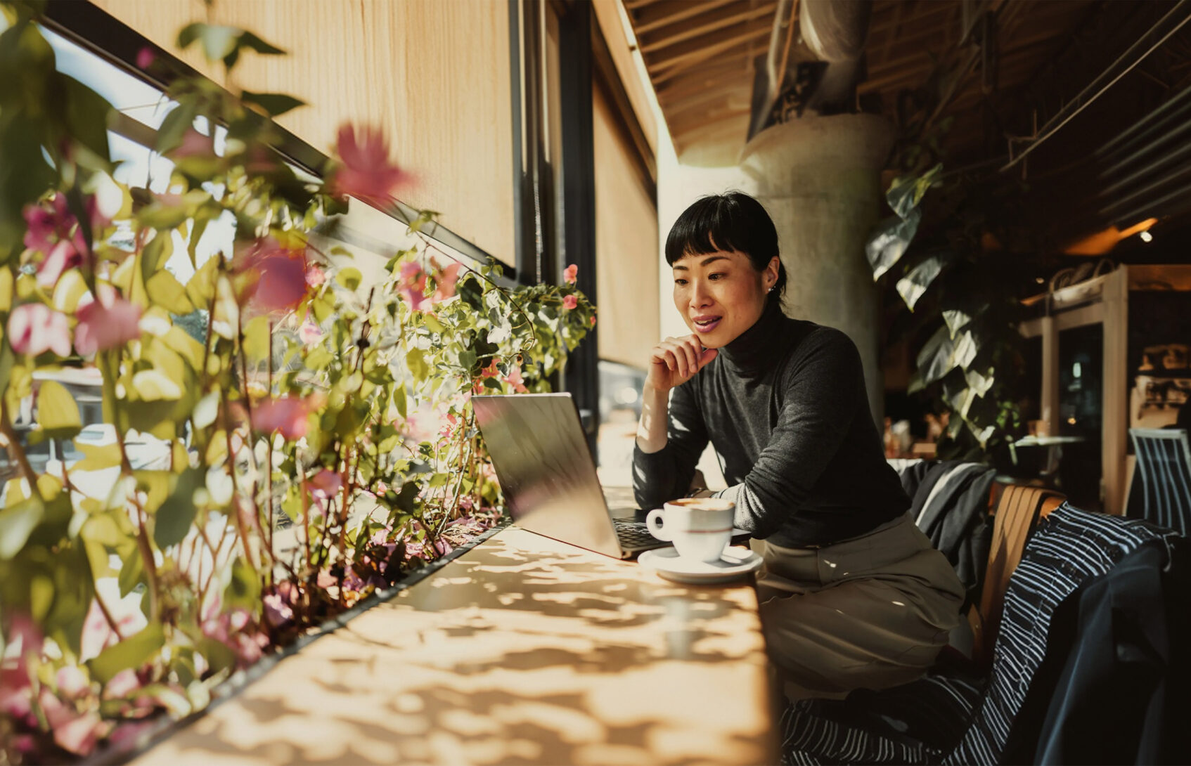 A woman sits in a café, working from her laptop computer.